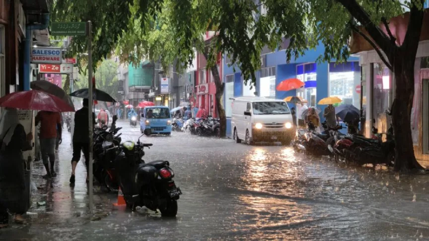 Flooded street in Male City with people and vehicles during heavy rain